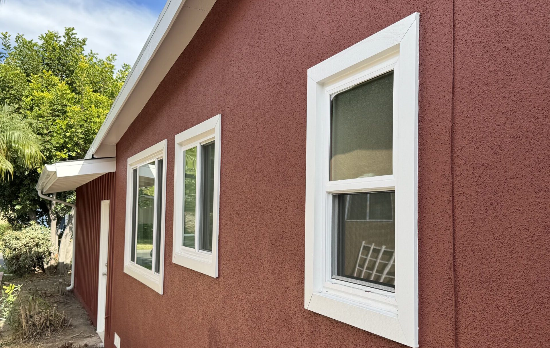 New windows with white trim on a red house